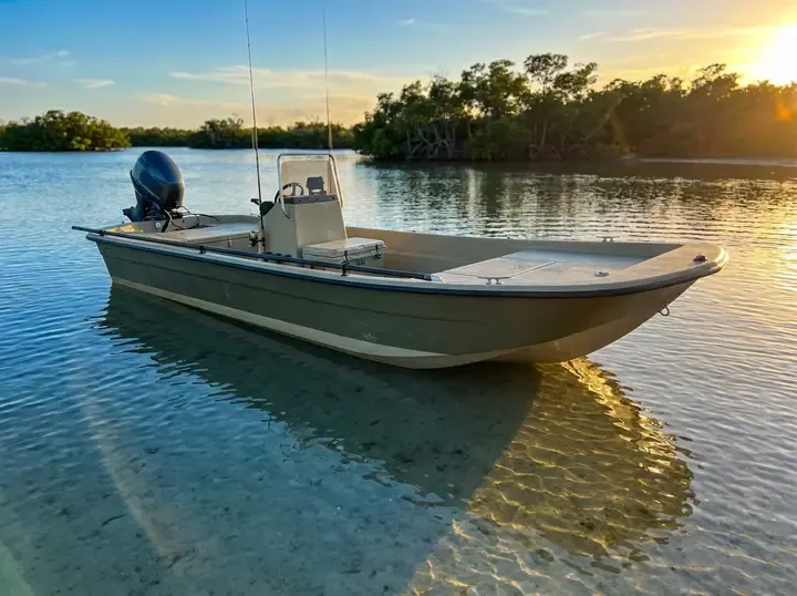 A compact 14-foot flat-bottom skiff on a clear saltwater flat at golden hour.